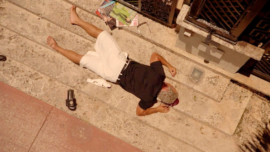 Versace morto nas escadas ao lado de uma pomba em The Assassination of Gianni Versace