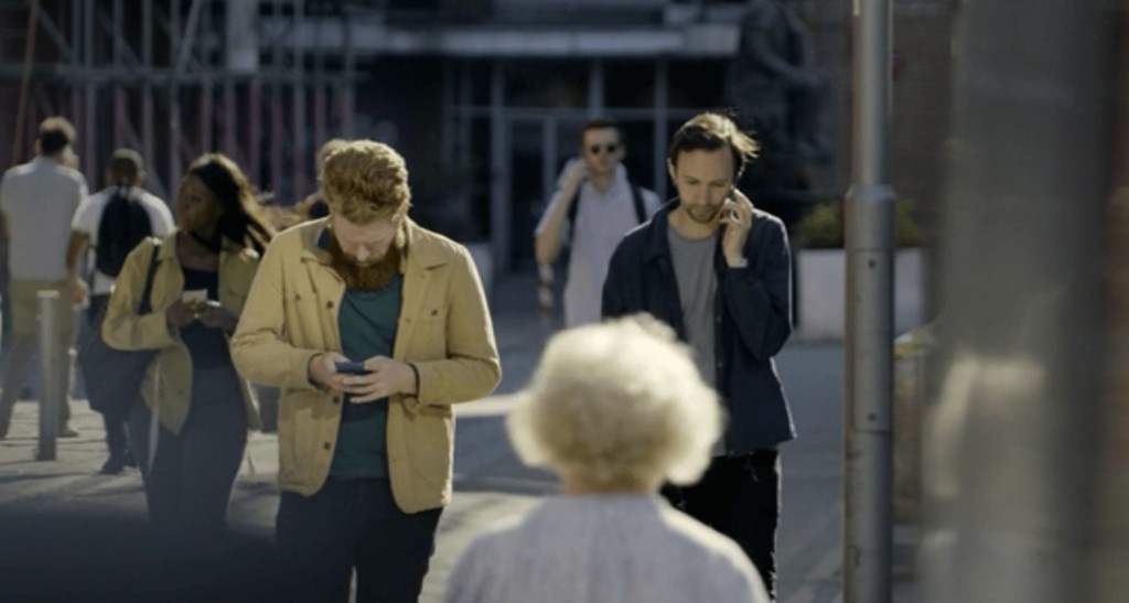 População anda na rua olhando o celular em Smithereens