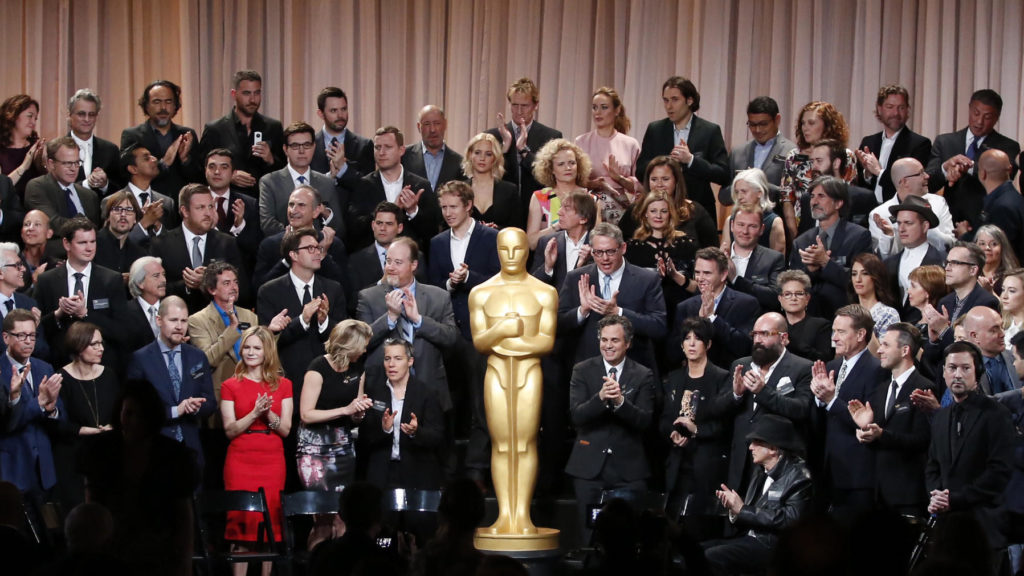 membros da Academia em volta da estatueta do Oscar