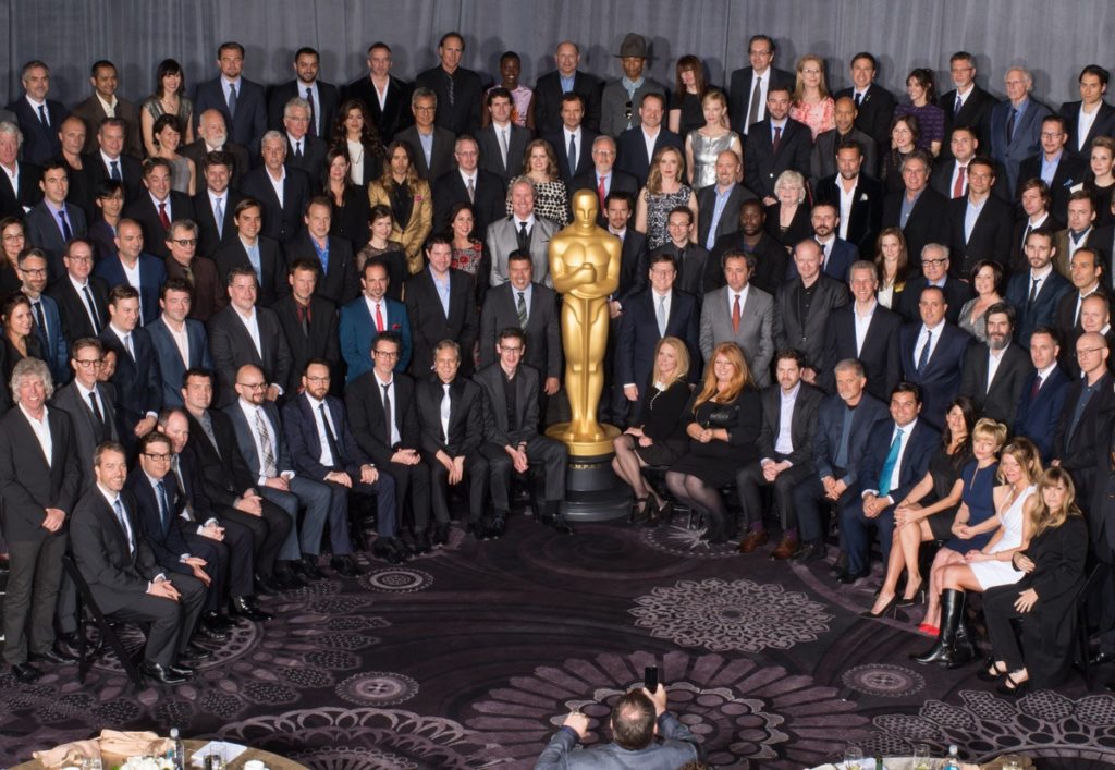 membros do Oscar sentados em volta da estatueta